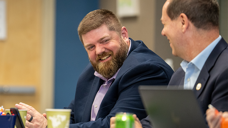 Man smiling at coworker who is laughing