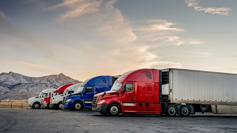Three semitrucks in front of the mountains