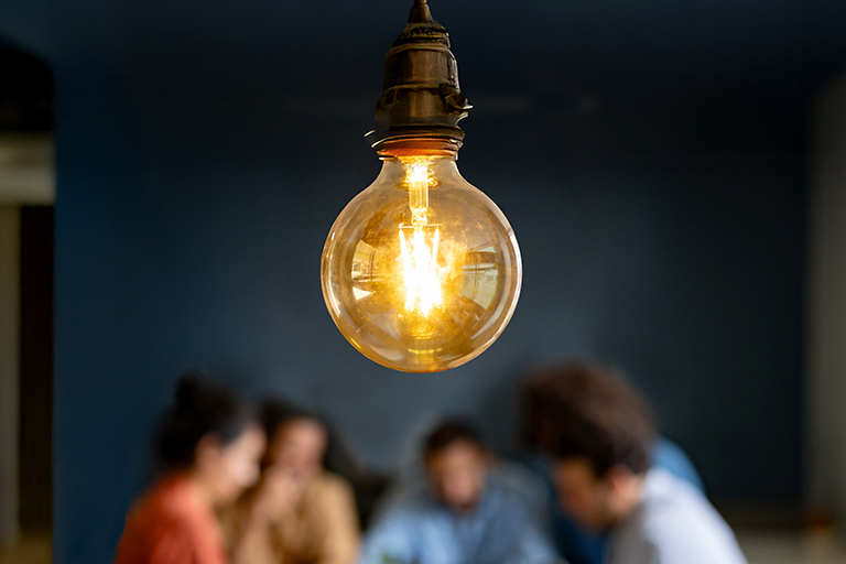 people around table with a light bulb in focus