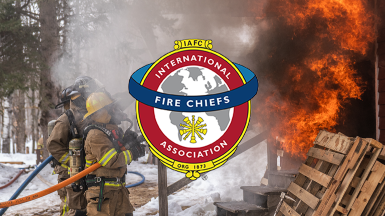 IAFC International Fire Chiefs Association logo displayed over a photo of a firefighters in full gear at a fire scene