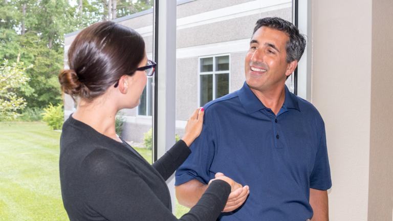 a member of the Sourcewell team shaking hands and greeting a new employee at the front door of the office