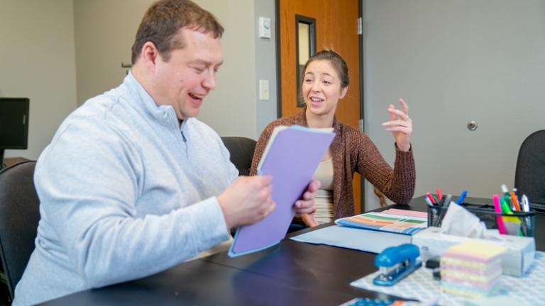 two individuals working together at table
